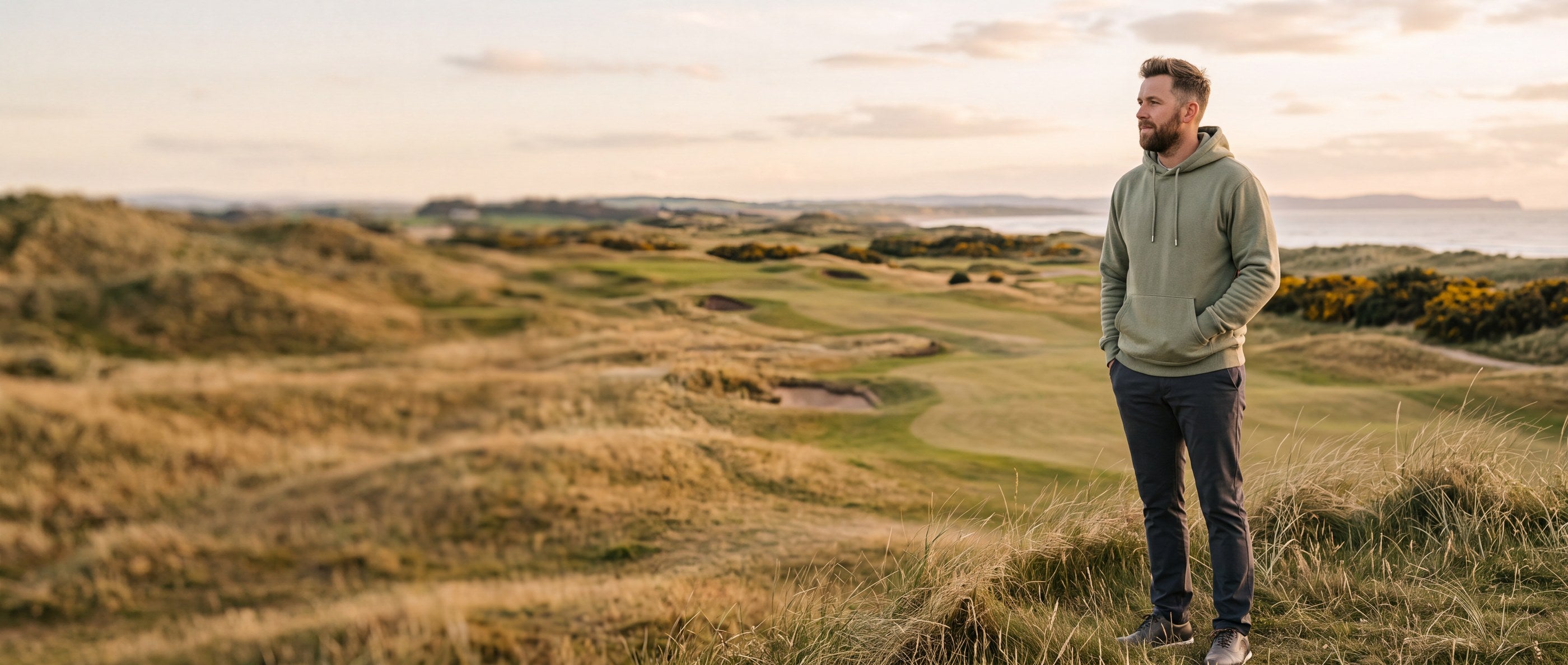 Golfer in a sage green hoodie on a links course at golden hour