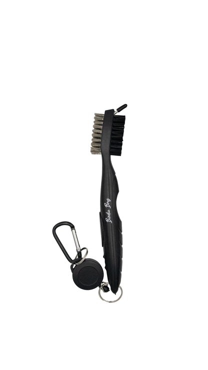 Black metal scrub brush with carabiner and retractable cord, designed for outdoor use.